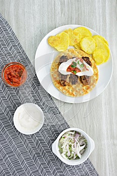 Kebab giaourtlou, french fries and  bowls with chopped onions, yogurt and tomato sauce