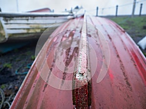 Keel ship of an old fishing boat in focus. Red hull. Background out of focus and in a mist