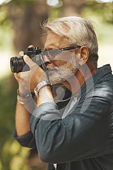 A keen elderly man with a beard takes pictures. Active leisure and hobby that inspires