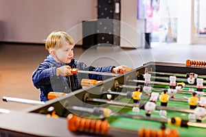 A keen and surprised boy plays table football