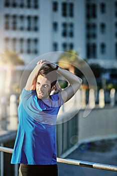 Keep the body loose and limber. a young man stretching outside before his run.