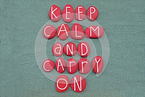 Keep Calm and Carry On, creative slogan composed with red colored stone letters over green sand