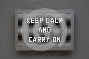 `Keep calm and carry on` words on a black lightbox on a black background, top view. Flat lay, overhead, from above
