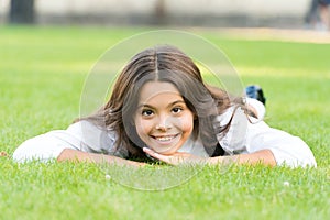 Keep calm and relax. Happy child with school look lying on green grass. Little girl smile with formal fashion look