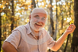 Keep cheerfulness. Pensioner hiking in forest on sunny autumn day. See beauty in simple things. Old bearded man collect photo
