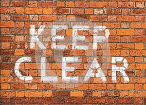 Keep Clear sign painted on brick wall