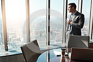 Keep a clear vision of where you strive to be. a young businessman looking out the window in an office.