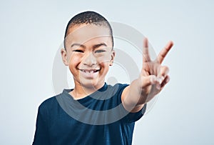 Keep it cool yall. Studio shot of a cute little boy making a peace sign against a grey background.