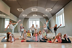 Keep dancing. Group of happy little boys and girls in fashionable clothes posing together in the dance studio. Dance