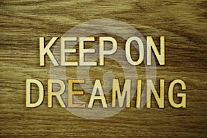 Keep On Dreaming text message on wooden background