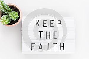 Keep the Faith, text written on a light box. Decorated with cactus