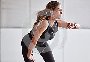 Keep going until you make good progress. a sporty young woman checking her watch while exercising outdoors.