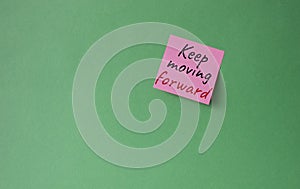 Keep moving forward symbol. Concept words keep moving forward on pink steaky note. Beautiful green background. Business and keep