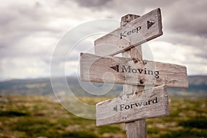 keep moving forward text engraved on old wooden signpost outdoors in nature