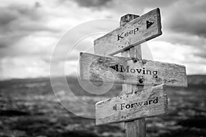 Keep moving forward text on wooden rustic signpost outdoors in nature/mountain scenery.