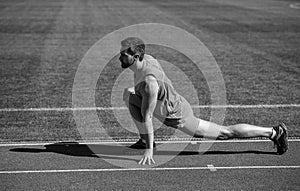 keep moving. sportsman relax. athlete train his flexibility. be flexible. man doing stretching exercise on stadium