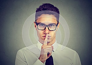 Keep my secret. Businessman holding finger on lips looking at camera