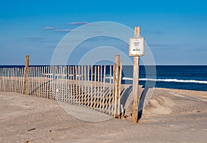 A Keep Off sign and fence on fragile sand dunes