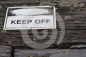 Keep off warning sign over old weathered rustic wooden textured