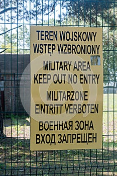 Keep out no entry inscriptions in Polish, English, German and Russian languages. Inscription on fence of military base