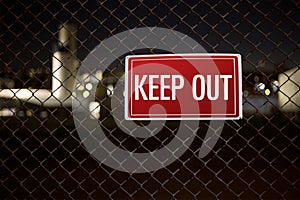 Keep out warning sign on a chainlink fence during night guarding private property