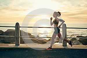 Keep putting one foot in front of the other. a sporty young woman running along the esplanade.