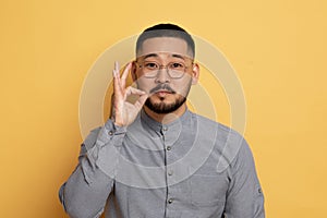 Keep Quiet. Asian Man Making Zipping Mouth Gesture, Holding Fingers Near Lips