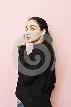 Keep quiet sign. Portrait of a beautiful woman in casual clothing showing hand gesture keep silence. Tss, Shh