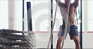 Keep on raising your game. 4k video of a muscular young man working out with heavy ropes at the gym.