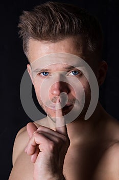 Keep silence. Attractive guy. Shhhh. the man asks to keep a secret