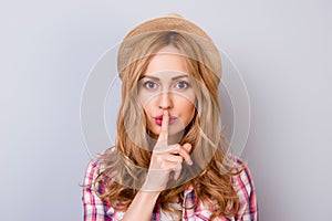 Keep silence! Portrait of young pretty woman holding her finger near lips and making silence gesture