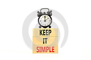 Keep it simple symbol. Concept word Keep it simple on beautiful wooden block. Black alarm clock. Beautiful white table white