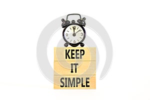 Keep it simple symbol. Concept word Keep it simple on beautiful wooden block. Black alarm clock. Beautiful white table white