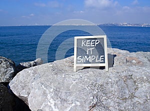 Keep it Simple symbol. Concept words Keep it Simple on chalk blackboard. Beautiful sea background. Business and Keep it Simple