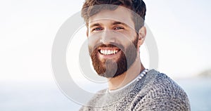 Keep smiling, keep growing that beard. a handsome young man spending the day at the beach.