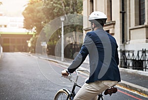 Keep steering forward. Rearview shot of a handsome young businessman riding his bicycle to work in the morning.