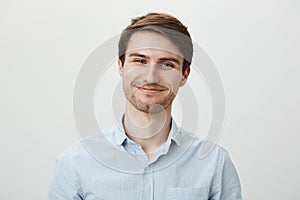 Keep talking but I do not care. Portrait of polite bothered attractive office worker in casual shirt pulling fake smile