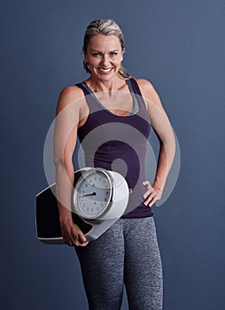 Keep track of your weight. Studio portrait of an attractive mature woman holding a weightscale against a blue background