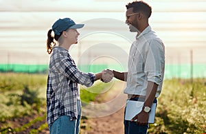 Keep up the good work. Cropped shot of two young farmers shaking hands while working on their farm.