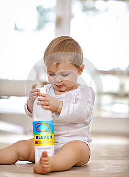 Keep your children safe - keep harmful items out of reach. Shot of a little baby playing with a bleach bottle.