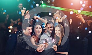 Keep your life sparkly and party a little. Cropped shot of a diverse group of young friends having fun with sparklers at