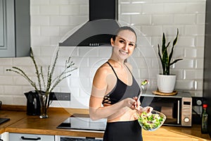 Young woman eats salat in the kitchen photo