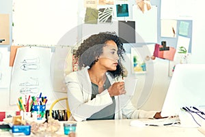 Keeping abreast of current fashion trends and fads. a designer working on her computer in her office.