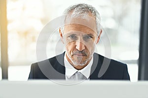 Keeping abreast of the newest business trends. a focused mature businessman working on his computer in an office.