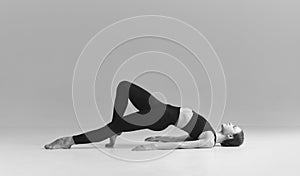 Keeping body fit. Black and white photography. Young girl doing stretching exercises over studio background. Concept of