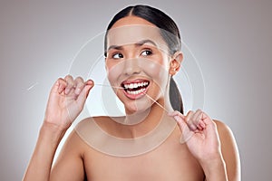 Keeping every tooth in tiptop shape. Studio shot of a beautiful young woman flossing her teeth against a grey background photo