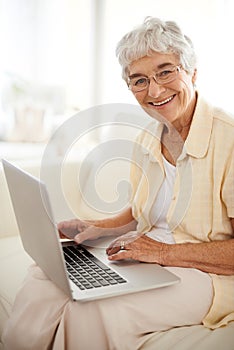 Keeping her blog followers happy. An aged woman working on a laptop from home.