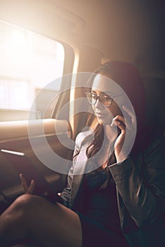 Keeping her business moving forward. Shot of a young businesswoman talking on a phone while using a digital tablet in