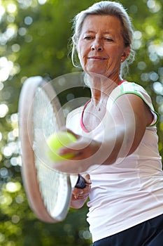 Keeping her eye on the ball. Senior woman getting ready to serve - Tennis.