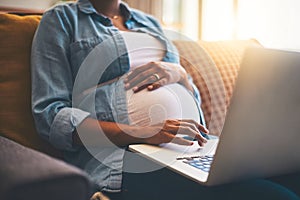 Keeping her pregnancy an informed one. a pregnant woman using her laptop at home.